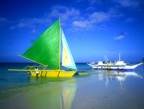 Pretty sailboat and men repainting a boat hull at low tide