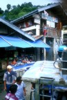 View of fish stand, laundry, and woman with child, taken from the top of the jeepney as we passed through the town of Banaue on our way to Batad