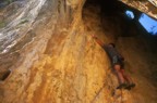 Clipping the first bolt; the route continues out the mouth of the cave at 6c