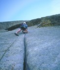 Moving up the .10a finger crack to the crux roof on the second pitch; the roof is climbed at the crack just above the helmet