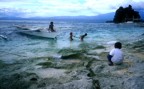 Some children playing at the beach on a small banca boat