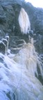 In heavy snow, Jim climbs the mixed rock and ice to get established below the pillar