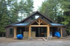 Head on view of the Hut; the trim and flooring are stored under blue tarps on the porch