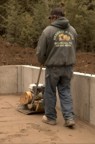 The excavation crew packs the sand with a tamping machine